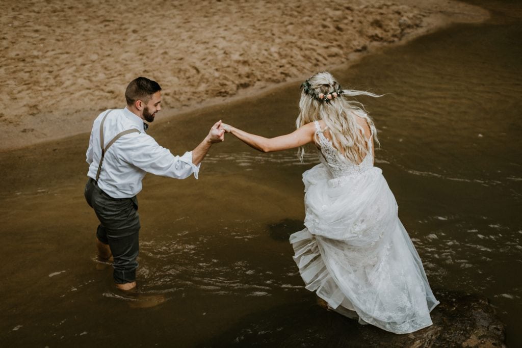 bride and groom exploring waterfall