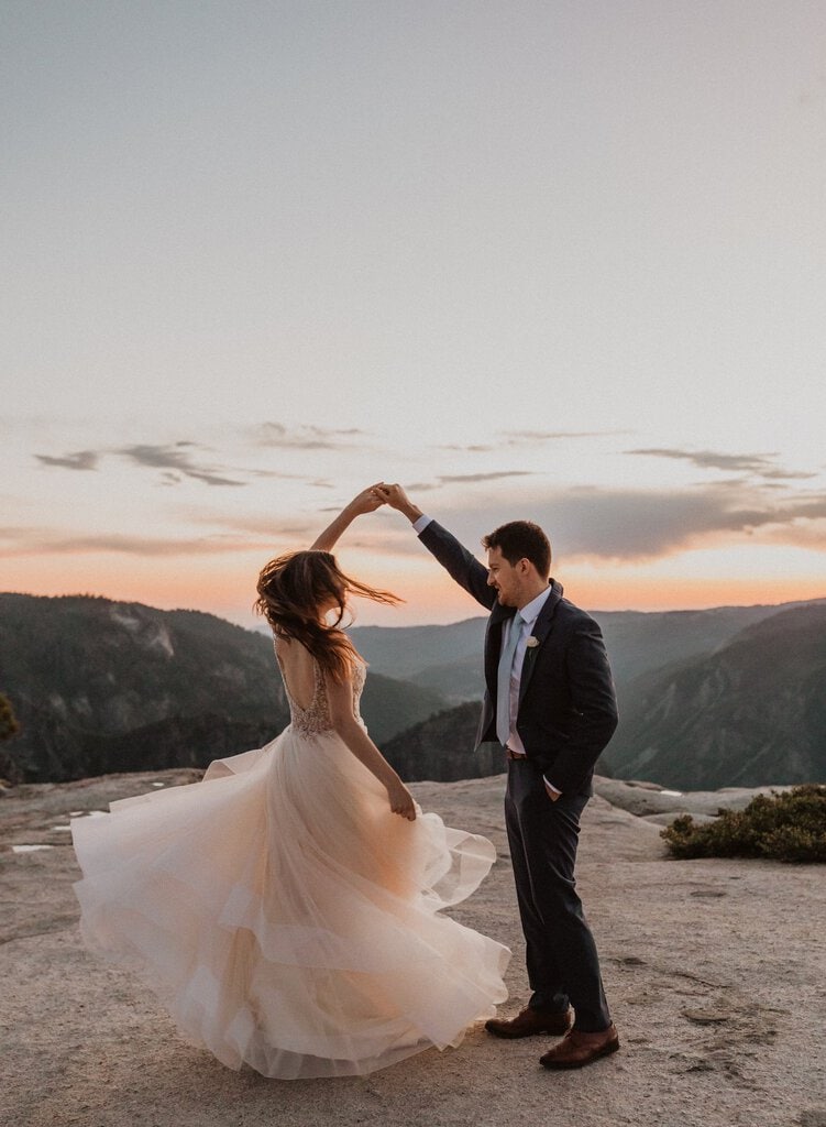 husband dances with wife on California mountain.