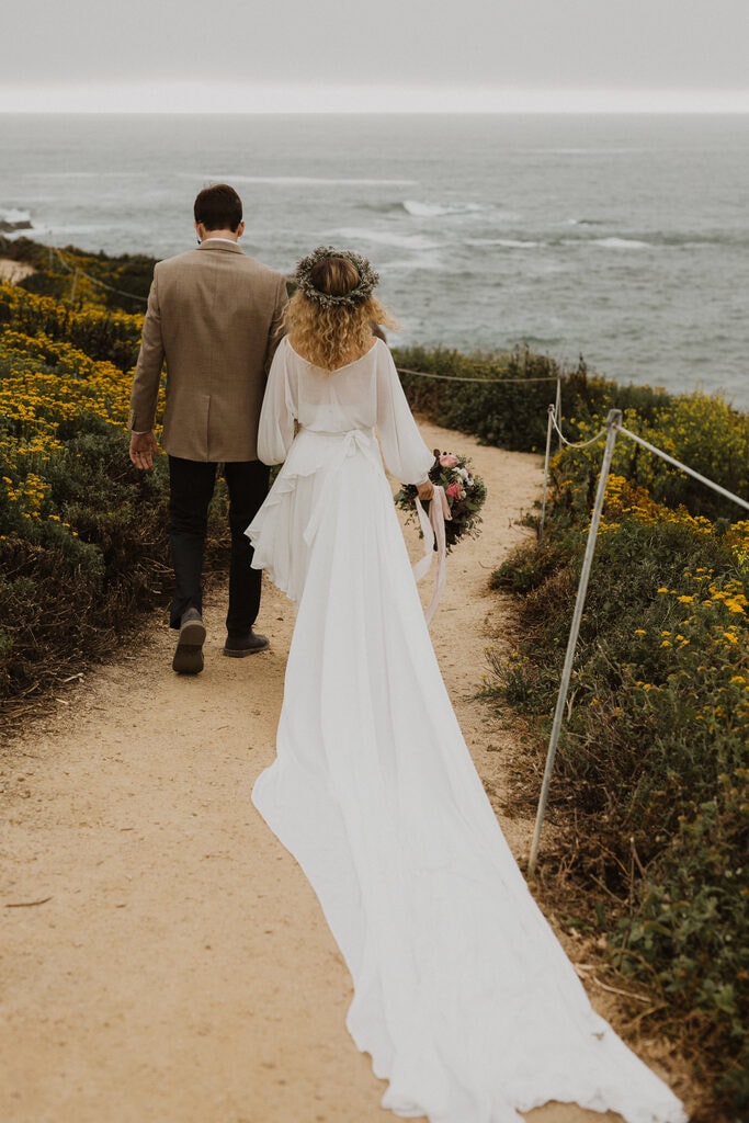 Bride and groom walking down the coast of California state park.