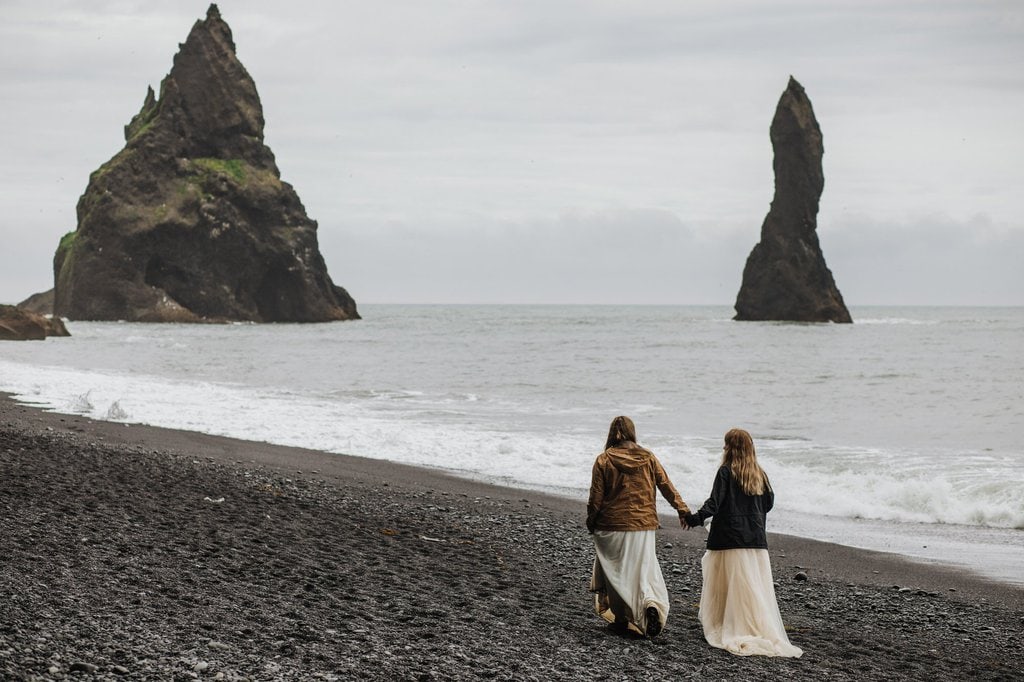 Brides walking down the black sand beach in Iceland.