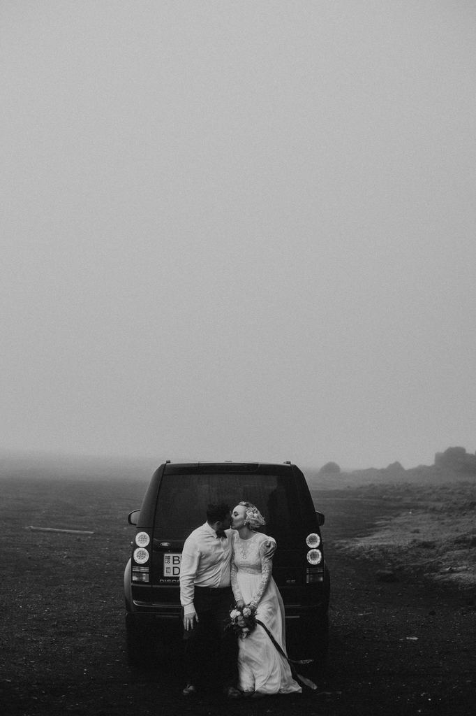 couple sitting by car in Iceland kissing.