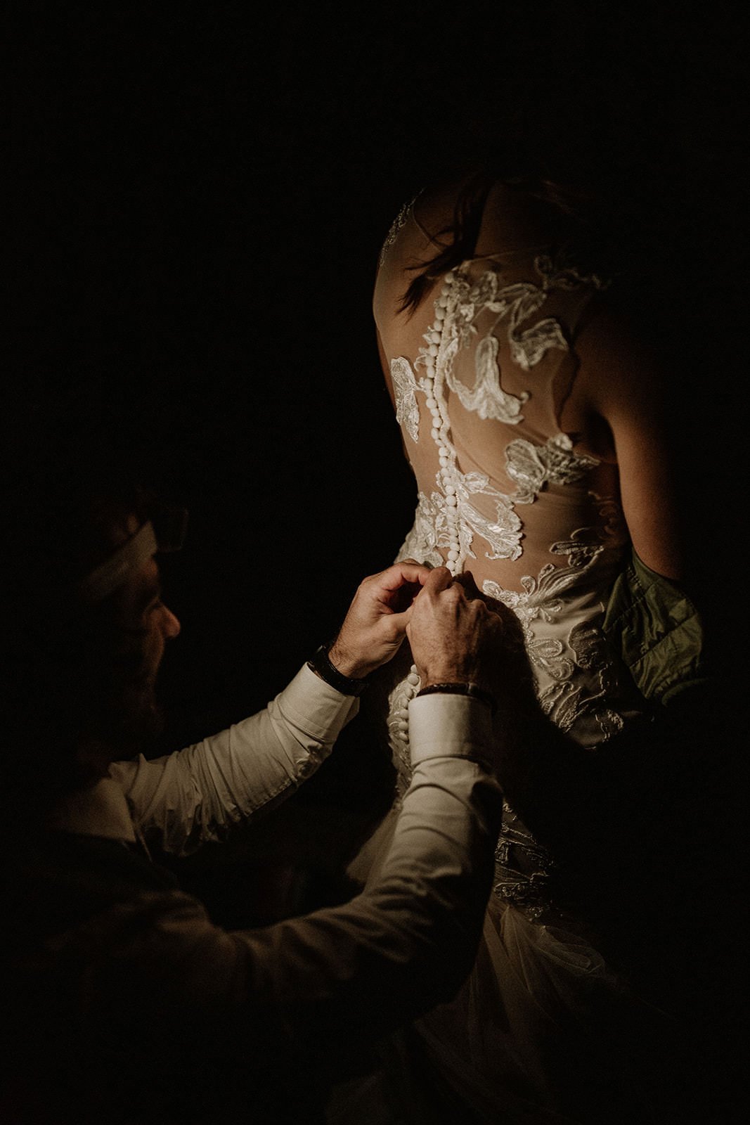 groom helping his bride get dressed