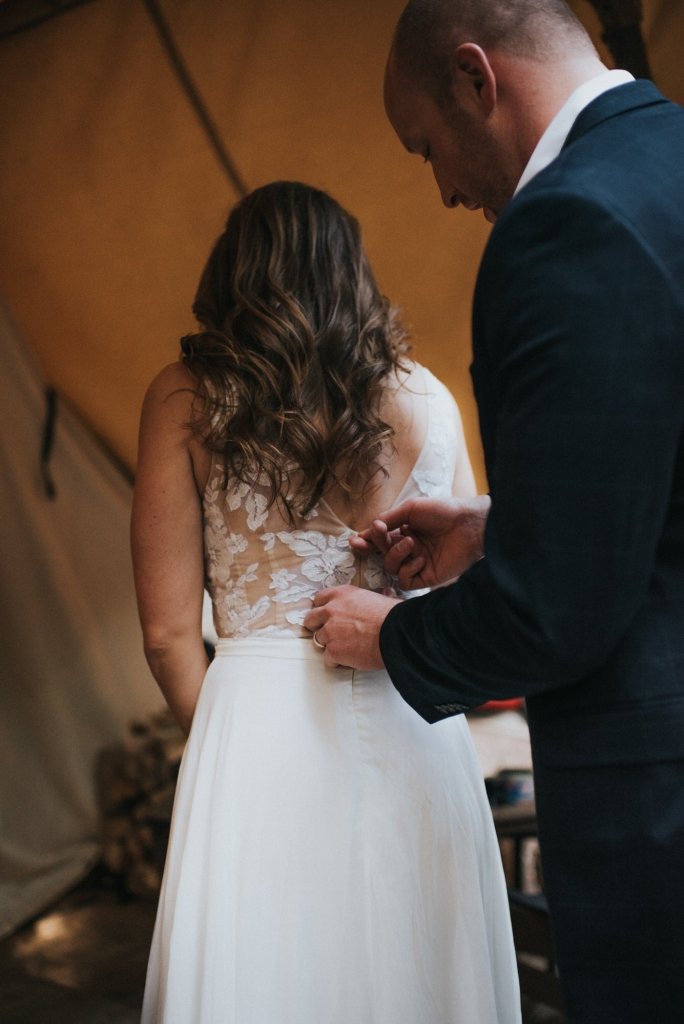 groom zipping wedding dress.