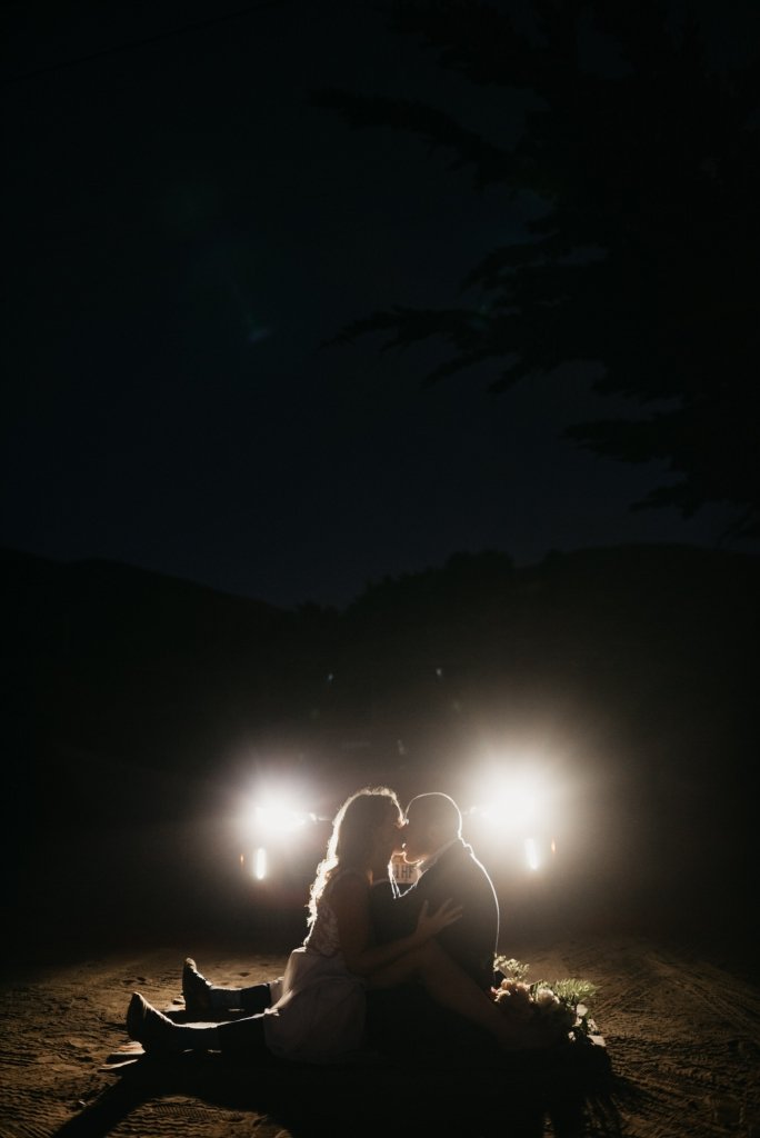 bride and groom kiss in the dark.