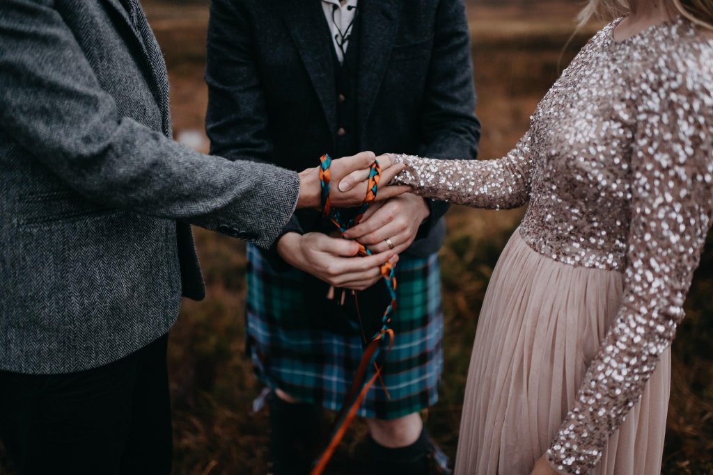 understanding what a celtic handfasting ceremony is and why it's perfect for engagements. Cords being wrapped around couple's hands.
